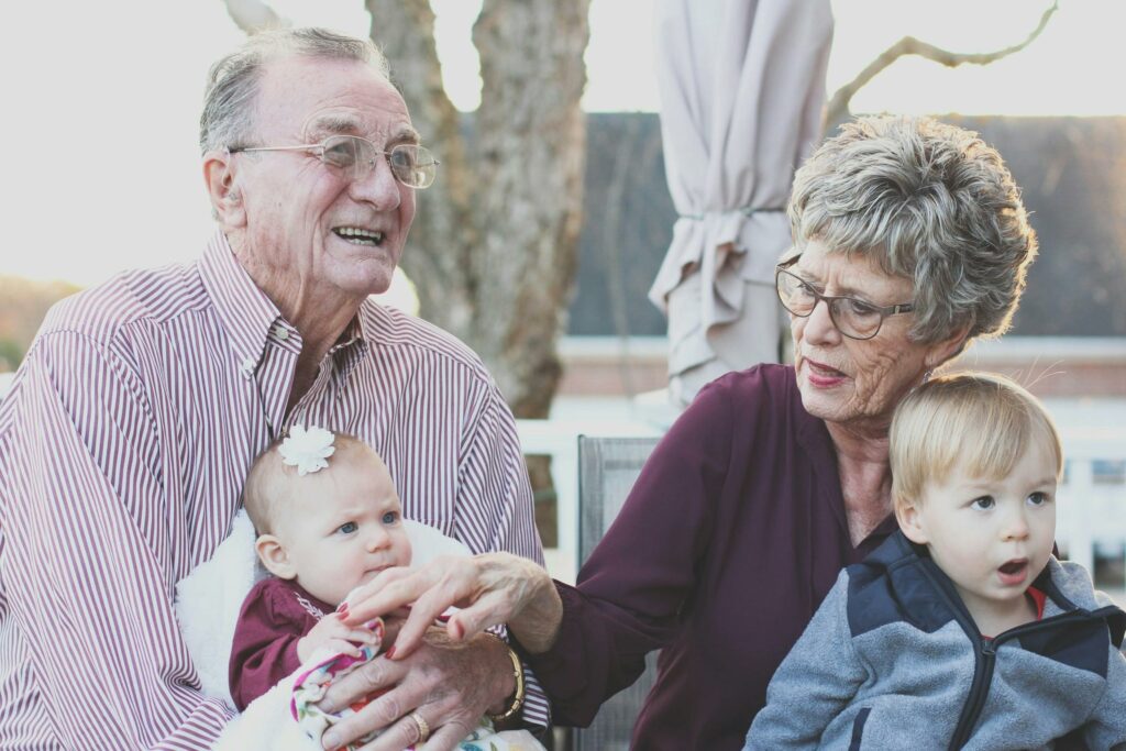 pexels-photo-302083-302083 Grandparents spending joyful moments with their grandchildren in an outdoor setting, captured candidly.